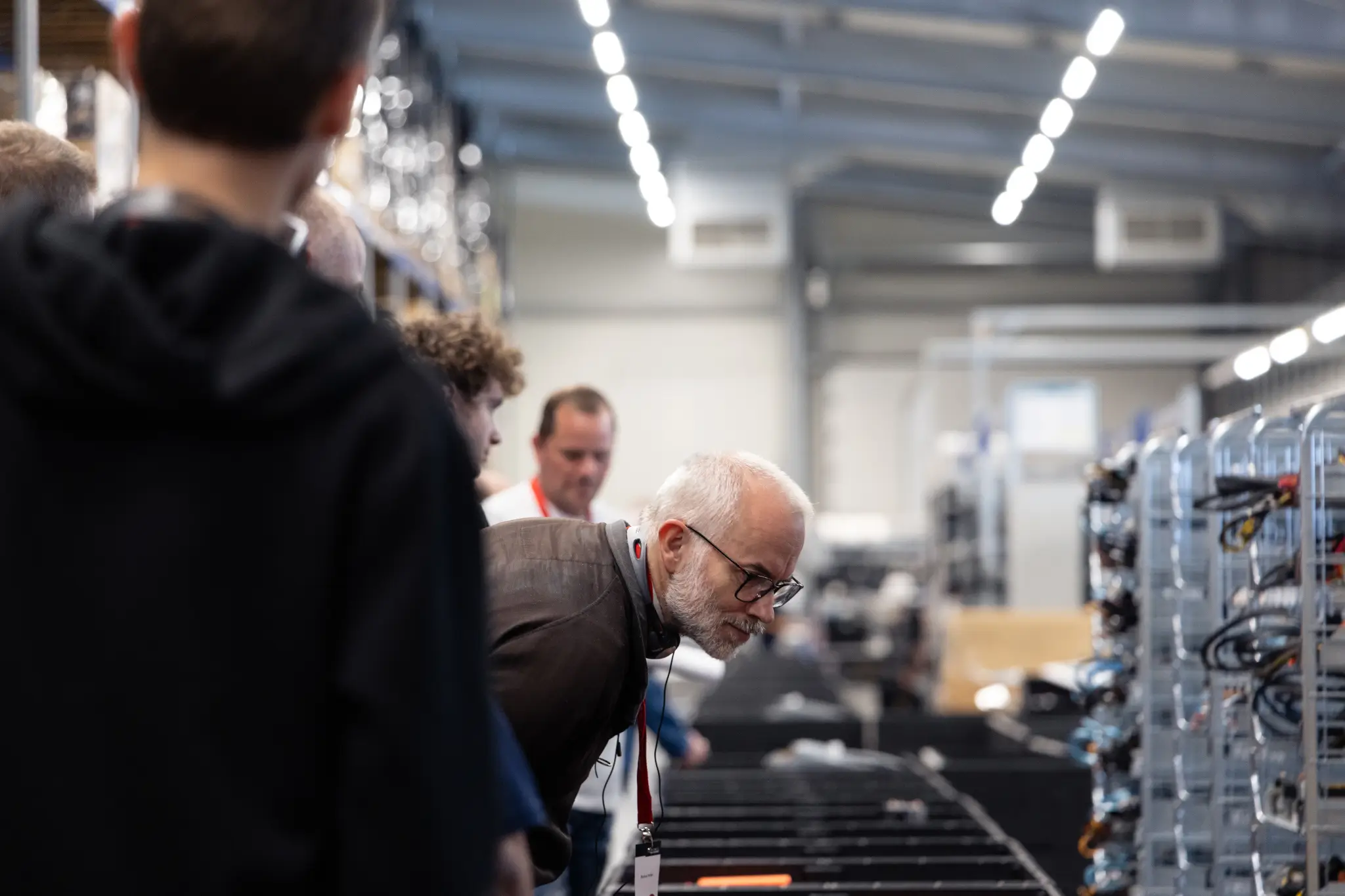 Man with glasses leans over server hardware in a data center hall.