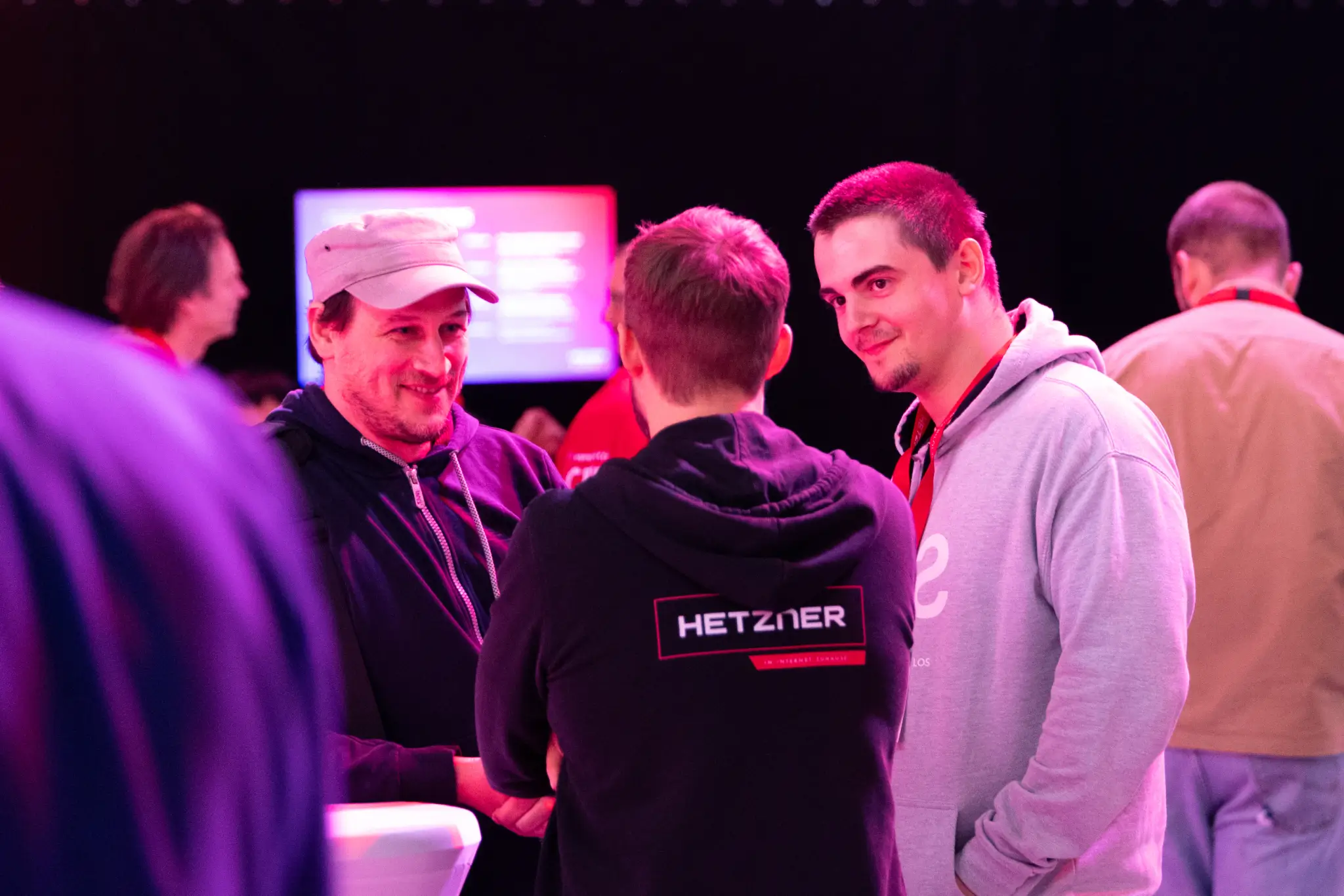 Group talking to a Hetzner expert wearing a hoodie with the Hetzner logo.