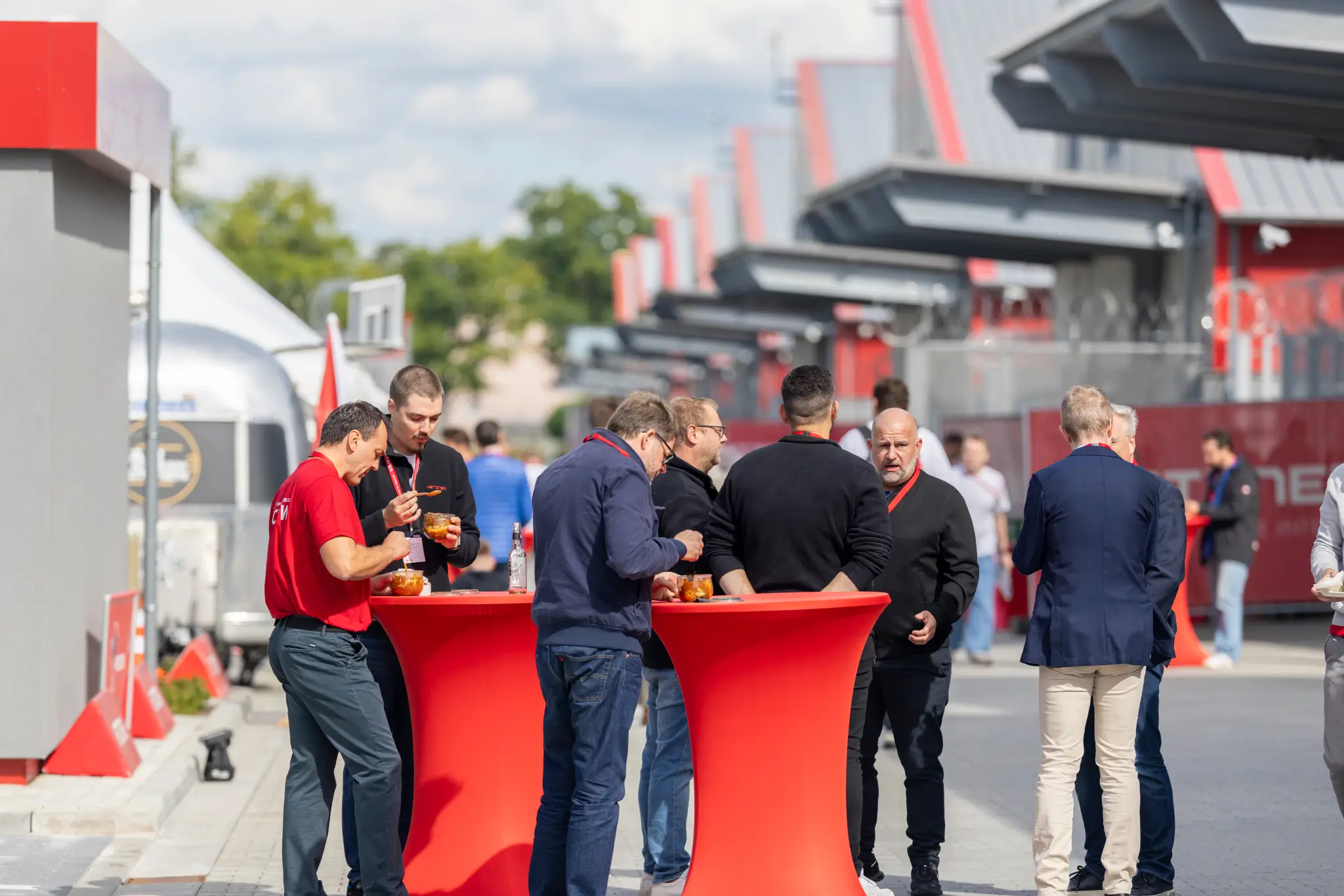 Guests stand at red high tables outdoors between data centers.